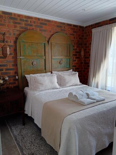 a bedroom with a bed and a brick wall at Spindrift Seaside Accommodation in Wilderness