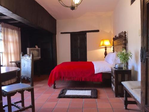 a bedroom with a large bed with a red blanket at Hotel San Luis de Ucuengá in Nobsa