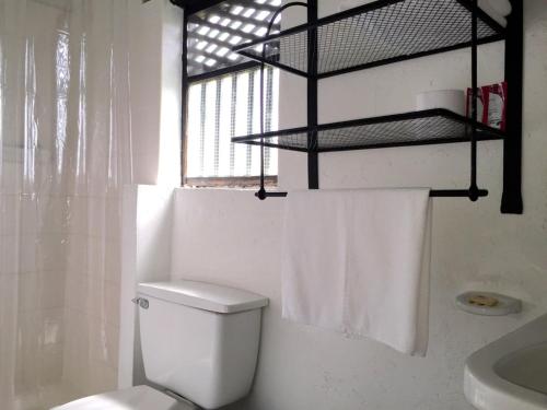 a white bathroom with a toilet and a window at Hotel San Luis de Ucuengá in Nobsa