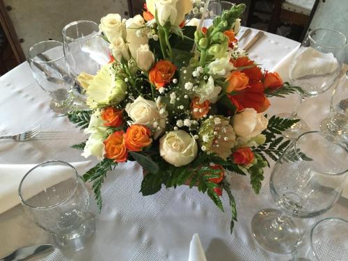 a table with a bouquet of orange and white flowers at Hotel San Luis de Ucuengá in Nobsa
