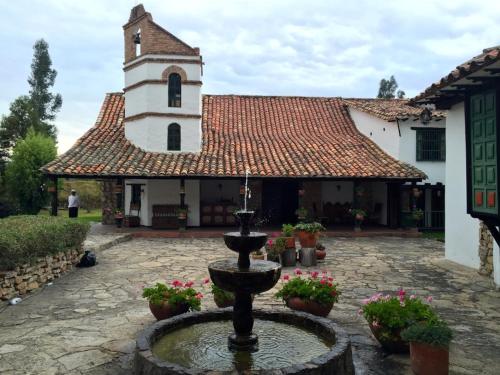 a fountain in front of a building with a clock tower at Hotel San Luis de Ucuengá in Nobsa