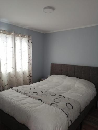 a bedroom with a bed with white sheets and curtains at Casa verano in Caldera