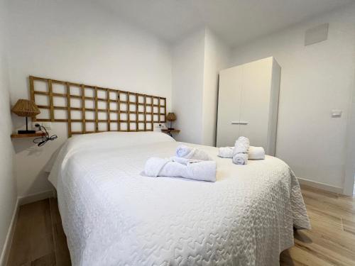 1 dormitorio con 1 cama blanca grande y toallas. en La paz y el sol del Obispo, en Málaga