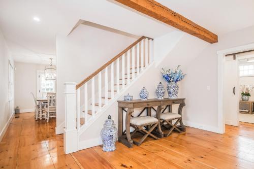 a dining room with a table and a staircase with blue and white vases at Sea Lyon in Nantucket