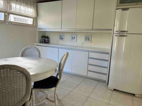uma cozinha com uma mesa e um frigorífico branco em Casa Canasvieiras Florianópolis com piscina e mar em Florianópolis