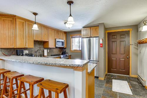 a kitchen with wooden cabinets and a counter with stools at Colorado Condo about 2 Mi to Winter Park Resort! in Winter Park