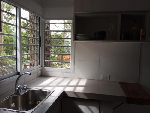 uma cozinha com um lavatório e duas janelas em Casa Buda em Villa Gesell