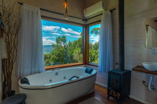 a bath tub in a bathroom with a large window at Pousada Colina do Sol in Urubici