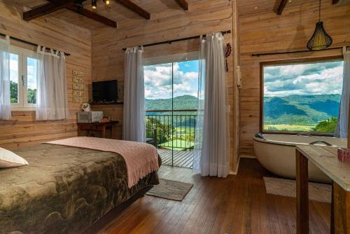 a bedroom with a bed and a tub and a window at Pousada Colina do Sol in Urubici