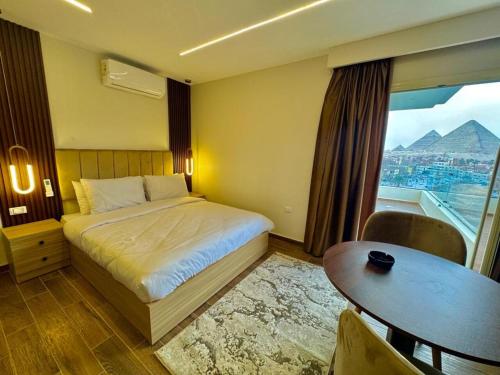 a bedroom with a bed and a table and a window at Rotana Pyramids View in Cairo