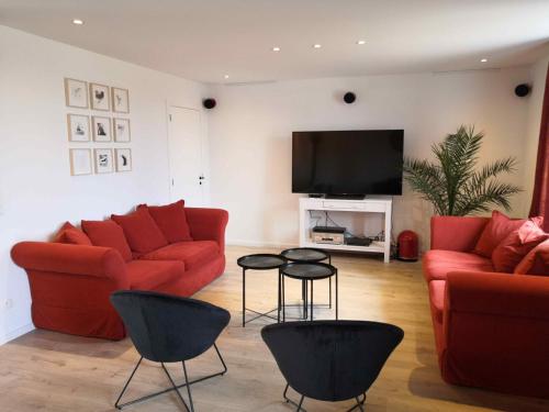 Aux Aguesses buissonnières في دربي: غرفة معيشة بها كنبتين حمراء وتلفزيون بشاشة مسطحة