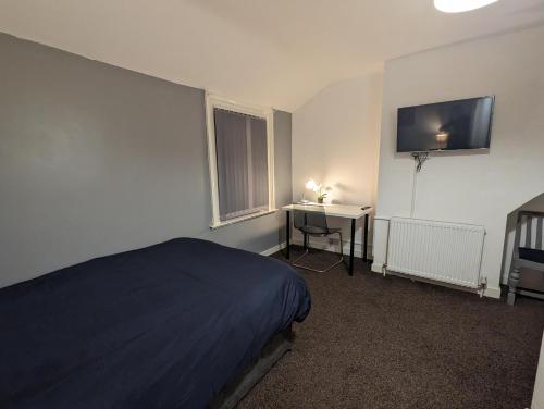 um quarto com uma cama, uma secretária e uma televisão em Paradise Street Contractor Haven em Barrow in Furness