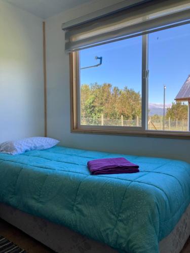Cama en habitación con ventana grande en Cabañas Don Diego_cabaña 1, en Puerto Montt