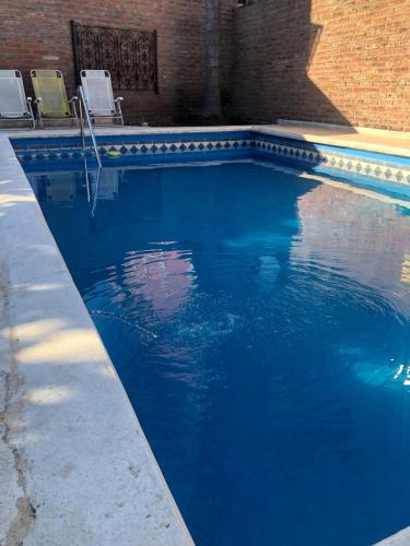 una piscina con 2 sillas y agua azul en complejo Casa Walter en Villa Carlos Paz