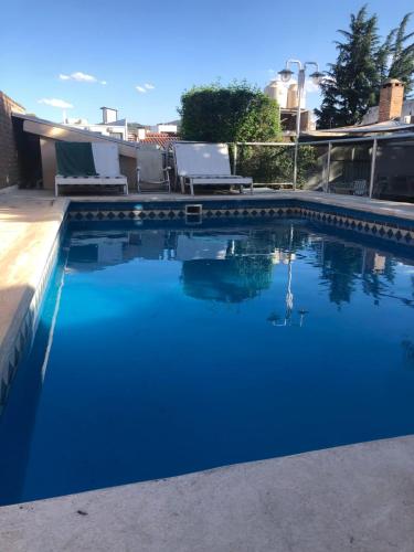 una piscina con agua azul y sillas blancas en complejo Casa Walter en Villa Carlos Paz