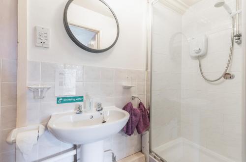 a white bathroom with a sink and a shower at Yallands Farmhouse in Taunton