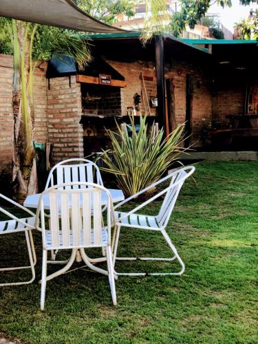dos sillas blancas y una mesa en un patio en complejo Casa Walter en Villa Carlos Paz