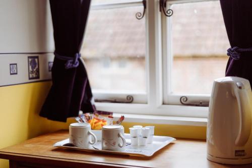 a tray of coffee cups on a table next to a window at Yallands Farmhouse in Taunton