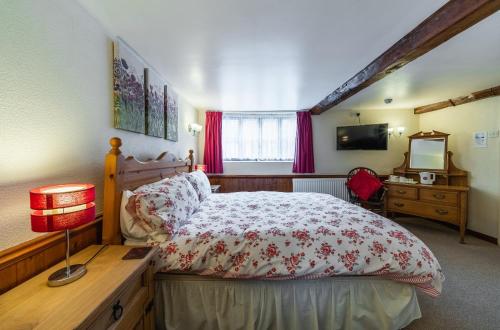 a bedroom with a bed and a desk and a television at Yallands Farmhouse in Taunton