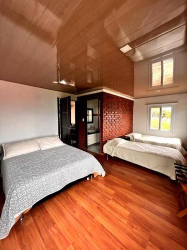 ein großes Schlafzimmer mit 2 Betten und Holzboden in der Unterkunft Cabañas Big Day Lago de Tota in Aquitania