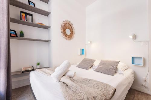 une chambre avec un lit avec des draps blancs et un miroir dans l'établissement Large Terrace 1 Bdr near Garibaldi Square, à Nice