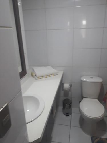 a white bathroom with a toilet and a sink at Bebo House, Merced in Santiago