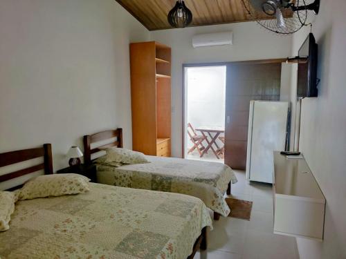 a room with two beds and a refrigerator in it at Recanto Solarium in Itanhaém