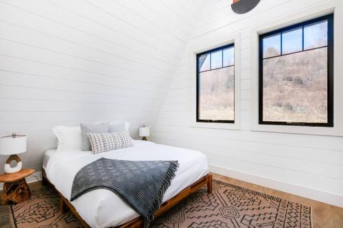 een witte slaapkamer met een bed en 2 ramen bij Mtn Views + Fire Pit + Secluded in Westfield