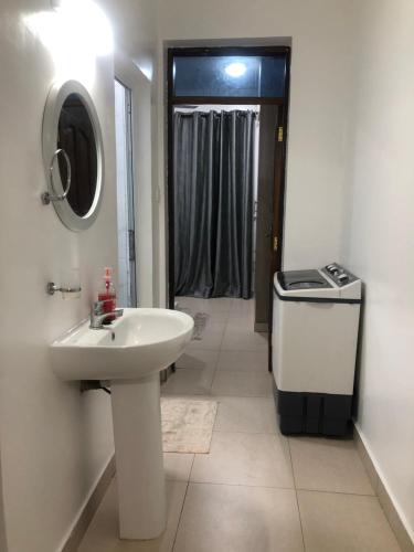 ein weißes Badezimmer mit einem Waschbecken und einem Spiegel in der Unterkunft Leisure apartment in Mombasa