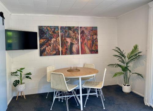 a dining room with a table and chairs and a painting at Oceans 88 Whitianga Coastal Suites in Whitianga