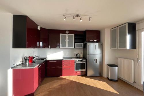 La cuisine est équipée de placards rouges et d'un réfrigérateur en acier inoxydable. dans l'établissement Spacious flat with terrace, à Saint-Denis