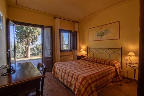a bedroom with a bed and a desk and a window at Agriturismo Buratta in Fonteblanda