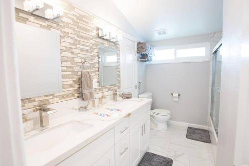 a white bathroom with a sink and a toilet at Safari Adventure: Arcade, Golf, Playground, Cars & More! in Garden Grove