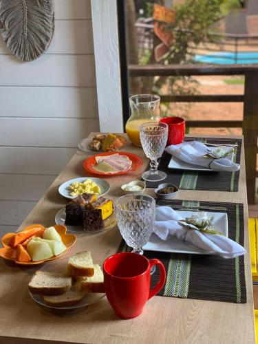 a table with plates of food and cups and drinks at Coração do Rosa - com Piscina Jacuzzi charme e conforto Pertinho do centrinho do Rosa in Praia do Rosa