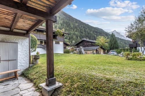 - une vue depuis la terrasse couverte d'une maison avec une cour herbeuse dans l'établissement Appartement Sous-Bois - Welkeys, à Chamonix-Mont-Blanc