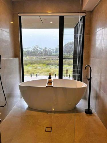 a large bath tub in a bathroom with a large window at Beach House in Inverloch