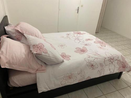 Bett mit rosa und weißer Bettwäsche und Kissen in der Unterkunft Claude et Carole in Obenheim