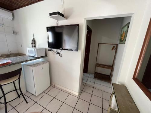 a kitchen with a refrigerator and a tv on the wall at Loft Canarinho - Praia do Campeche in Florianópolis