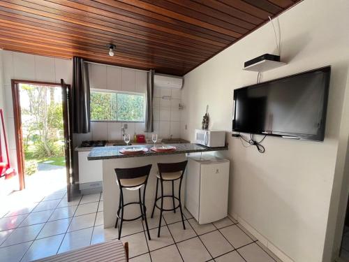 a kitchen with a counter and two bar stools at Loft Canarinho - Praia do Campeche in Florianópolis