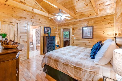 a log cabin bedroom with a bed and a ceiling fan at Smoky Bear Cinema in Sevierville
