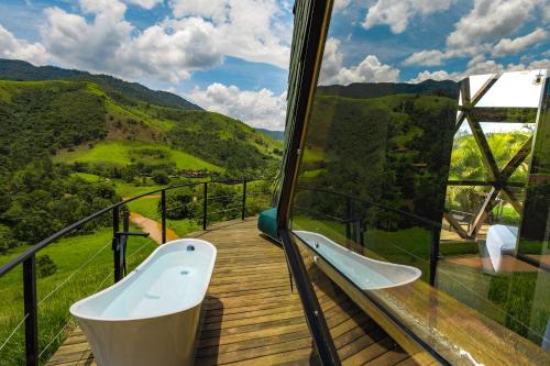 a balcony with a bath tub on a wooden deck at Freedome Domos e Chalés in São Francisco Xavier