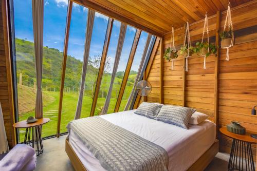 a bedroom with a bed in a room with windows at Freedome Domos e Chalés in São Francisco Xavier