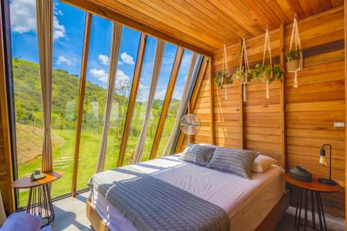 a bedroom with a bed in a room with windows at Freedome Domos e Chalés in São Francisco Xavier