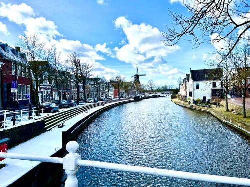 un río en una ciudad con un molino de viento a lo lejos en Chalet Jupp, en Lauwersoog