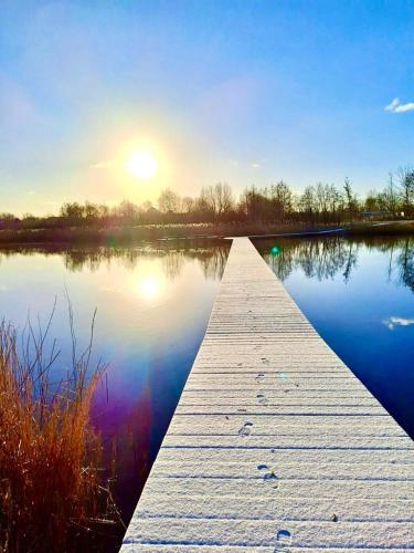 a dock on a lake with the sun in the background at Chalet Jupp in Lauwersoog