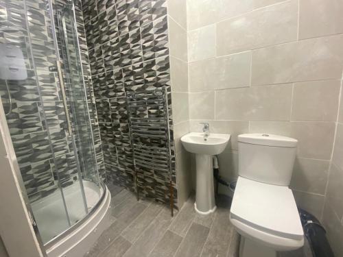 a bathroom with a toilet and a shower and a sink at Queens Hotel Blackburn in Blackburn