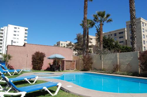 una piscina con 2 tumbonas y una piscina en De La Costa Cabañas, en La Serena