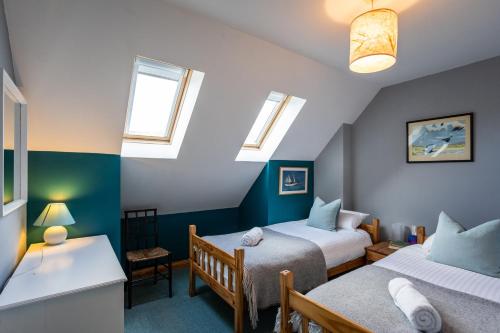 a bedroom with two beds and two windows at Shorefield, Bruichladdich in Bruichladdich