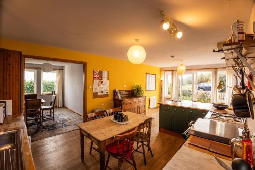 a kitchen with yellow walls and a wooden table at Shorefield, Bruichladdich in Bruichladdich