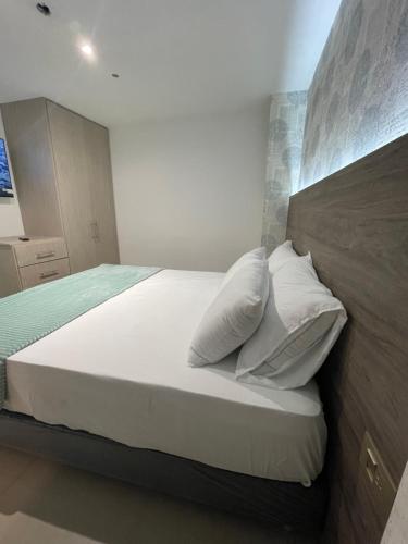 1 dormitorio con 1 cama con sábanas y almohadas blancas en Luxury liv Gran limonar, en Cali